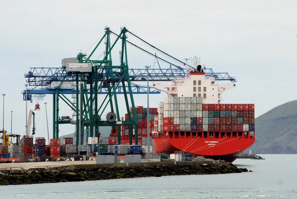 Container cranes loading a red container ship at a quayside